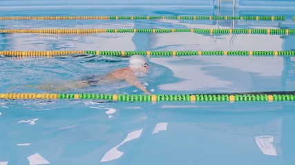 Senior man swimming in an indoor swimming pool.