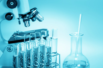 microscope and laboratory test tube on light blue background , science research equipment concept