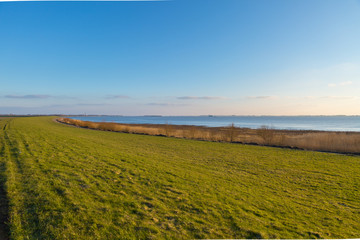 Green meadows line the riverside. Nature reserve on the Eider (river in Schleswig Holstein) - Tönning, Germany