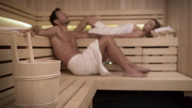Travelling young beautiful couple relaxing in a sauna. Interior of new resort spa sauna, classic wooden sauna.