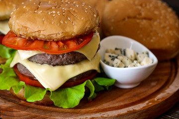 Homemade burger on wooden cutting board.