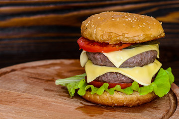 Homemade burger on wooden cutting board.