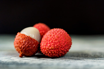 Three lychee fruits on dark background close