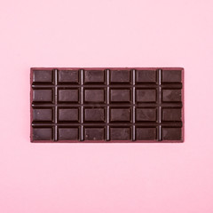 Dark chocolate bar isolated on a pink background