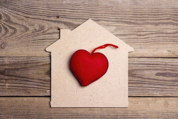 Home symbol with red heart on wooden background.