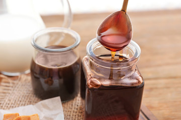 Obraz na płótnie Canvas Spoon with tasty caramel sauce over jar, closeup