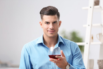 Handsome man with glass of wine relaxing at home