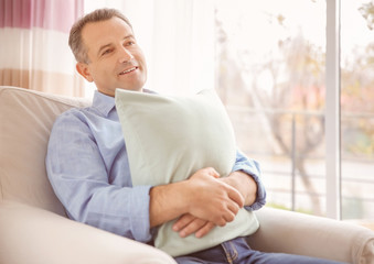 Mature man with soft pillow at home
