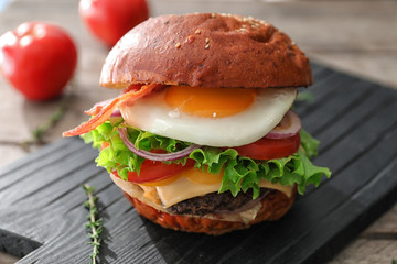 Tasty burger with fried egg on table
