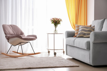 Living room interior with comfortable couch, rocking chair and soft pillows