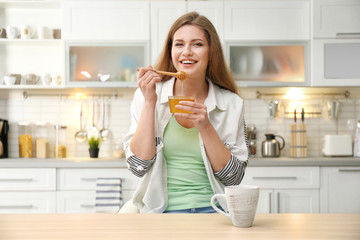 Positive young woman with honey in kitchen
