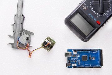 Arduino Mega board flat layout with caliper, stepper motor and multimeter on a marble background in isolation flat layout.
