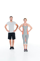 smiling couple in sportswear standing akimbo isolated on white