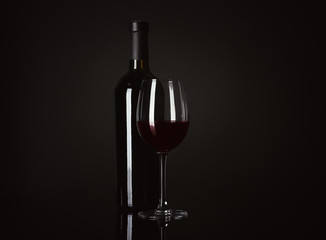 Bottle and glass with red wine on black background