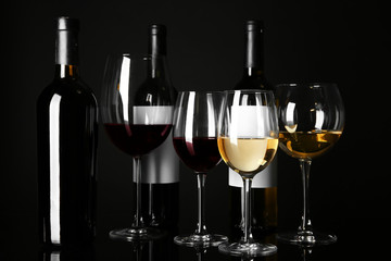 Glasses and bottles with different wine on black background