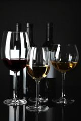 Glasses and bottles with different wine on black background