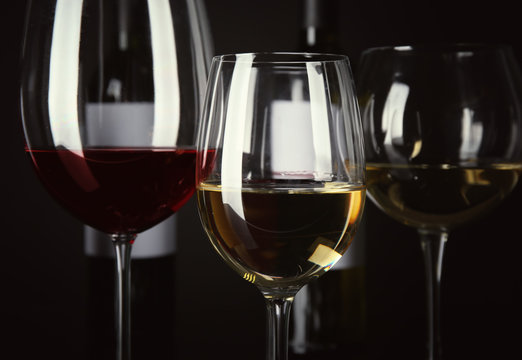 Glasses with different wine on black background