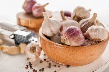 Bowl with fresh garlic on wooden board, closeup