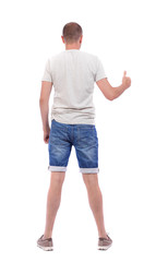 Back view of  man in shorts shows thumbs up.   Rear view people collection.  backside view of person.  Isolated over white background. A boy in denim shorts shows a thumbs up.