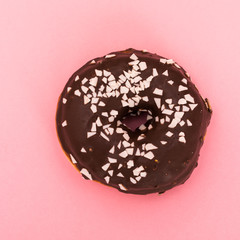 Donut with sprinkles isolated on pink background. Top view.