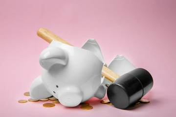 Broken piggy bank with money and hammer on color background