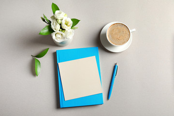 Beautiful flowers, cup of coffee and empty card on grey background