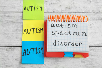 Notepad with text AUTISM SPECTRUM DISORDER on wooden background
