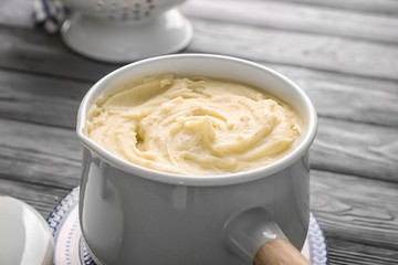 Cookware with mashed potatoes on wooden table