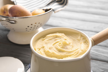 Cookware with mashed potatoes on wooden table