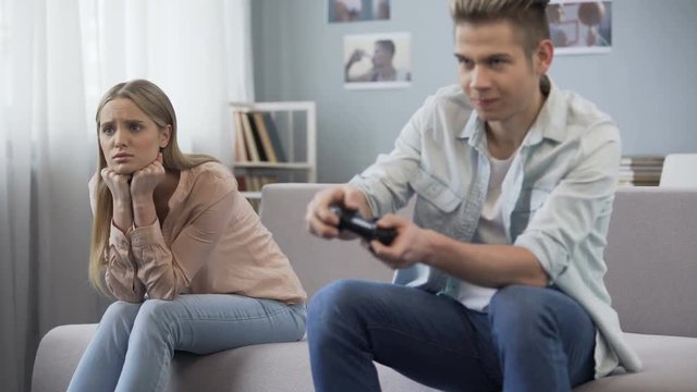 Boy excitedly playing video game without paying attention to girl sitting next