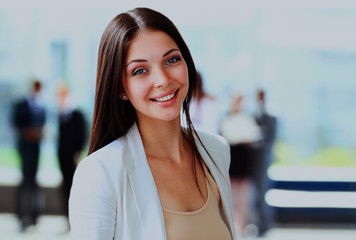 Happy young business woman standing in front of her team.