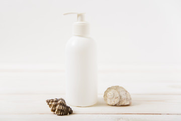 White cosmetic bottle,sea shells.wooden background