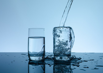 Creative splashing water in the glass on blue background.