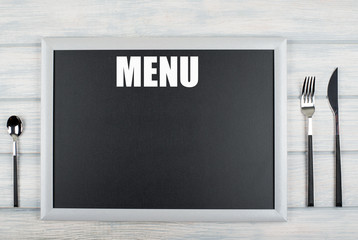 Blackboard with the word Menu written on it, among covered kitchen on wooden table. Menu. Food