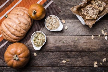 Rustic pumpkins with cookies and seeds on wood