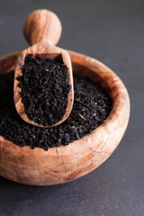 Black cumin or nigella sativa or kalonji seeds in bowl with spoon on black slate background, selective focus