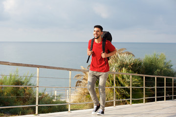 happy young male hiker with backpack by the sea