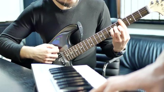 Man lead guitarist playing electrical guitar. Rock band practice play piano. Musician hands playing on electric piano with guitar player. Music band concert