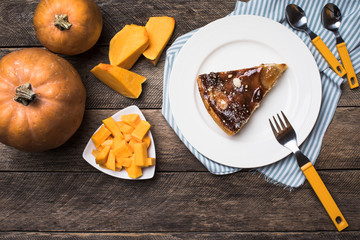 Tasty pie on plate and pieces of pumpkin in Rustic style