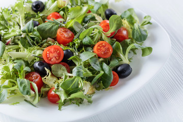 Green salad with tomatoes and black olives.