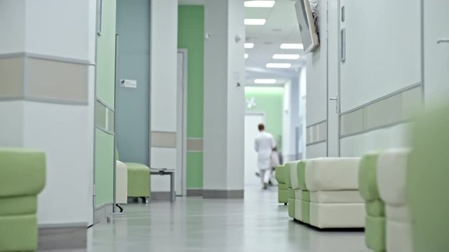 Panning shot of hospital corridor with light green ottomans