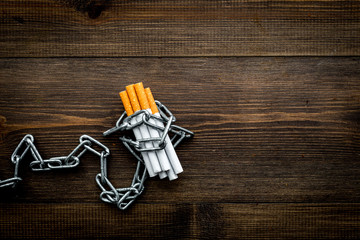 Quit smoking. Cigarettes in chains on dark wooden background top view copy space