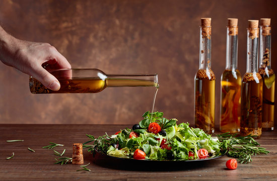 Green Salad With Olive Oil Pouring From A Small Bottle.