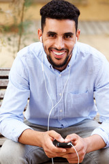 smiling North African man listening to music on mobile phone