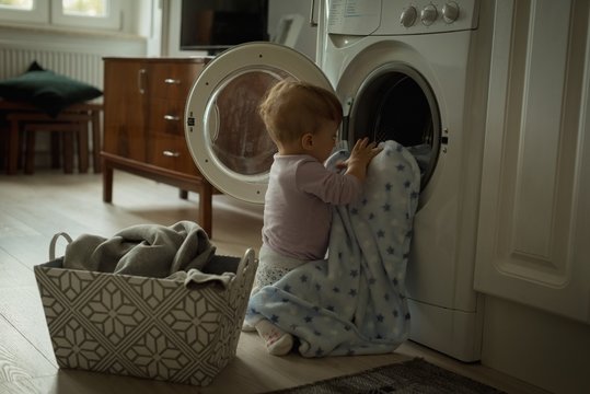 Baby putting clothes inside the washing machine