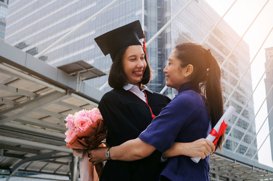 You Did It. Happy Asian Mother Hug With Flower And Congratulation Graduation To Her Caucasian Daughter, Family, Education, Proudly, Degree Certificate, Congratulation Ceremony And Successful Concept