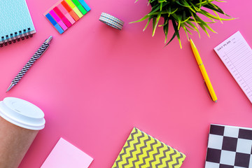 Student's desk. Notebook, stationery, coffee cup on pink background top view copy space