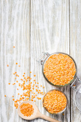 Dry red lentils in glass jar on white wooden background. Top view, copy space.