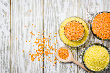 Dry red lentils and coucous in glass jar on white wooden background. Top view, copy space.