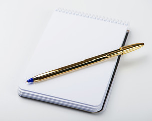 Notepad with blank paper next to golden ball pen on white background. Isolated. Mockup.